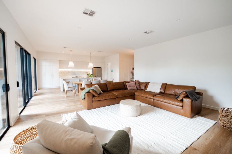Living room with a tan leather modular sofa, oak floors and large windows